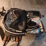 Open 40 litre carry-on backpack for solo travel with a vacuum bag of clothes, a combination cable lock, medicines in a zip pouch and a vacuum pump