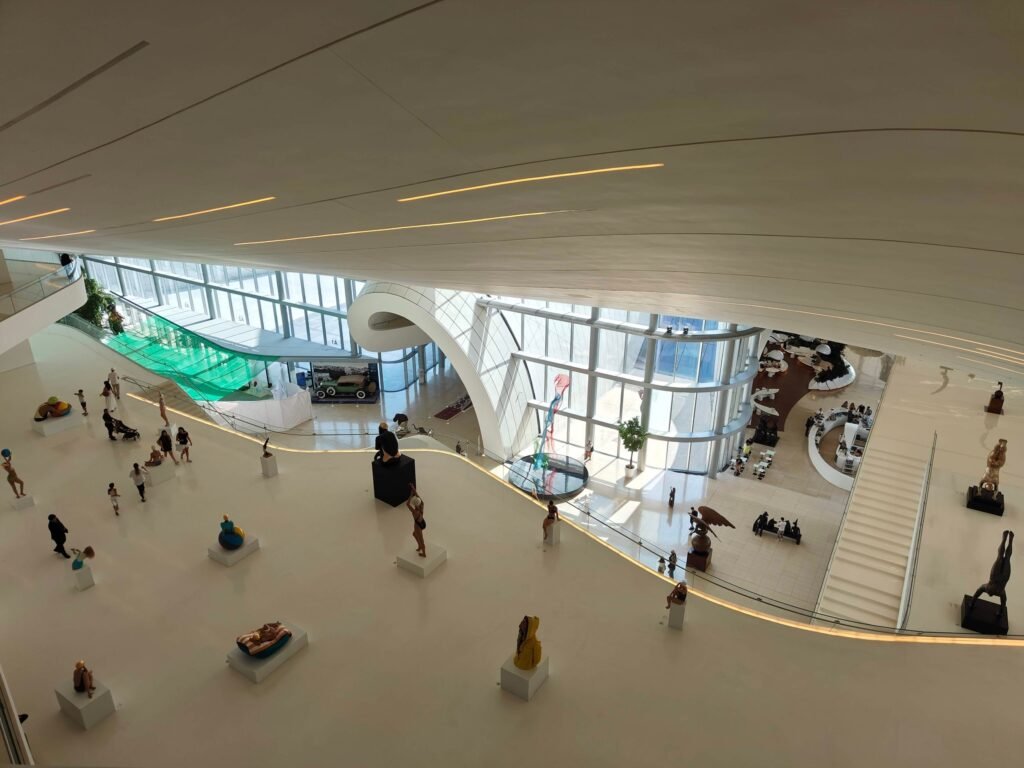 Inside the Heydar Aliyev Center in Baku, a curving white hall with sculptures of swimmers